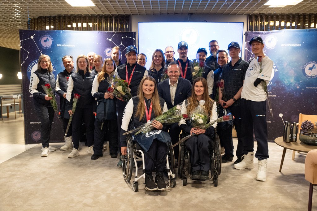 Suomen paralympiajoukkue ja tukijoukot yhteiskuvassa Mika Poutalan kanssa paluujuhlassa.